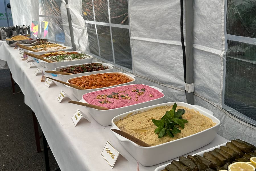 Lange weiße Buffet-Tafel im Zelt mit Sarma, Hummus und weiteren Mezze, jede Schale beschriftet