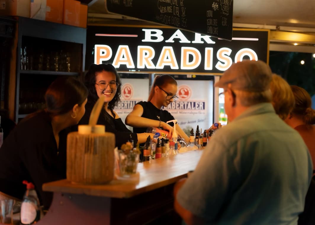 Lachende Mitarbeiterin an der Bar Paradiso, Gäste am Tresen