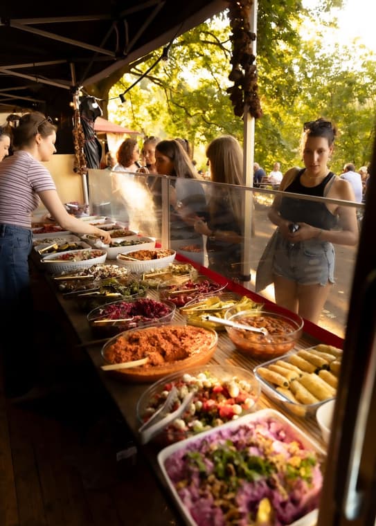 Reich gedecktes Mezze-Buffet am Stand, eine Gästin sucht sich etwas aus