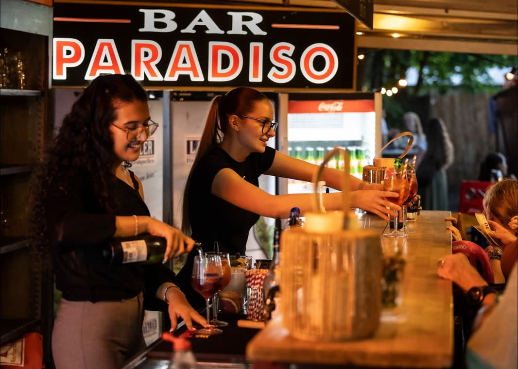 Mimi und Aylin schenken an der Bar Paradiso aus, darüber das Leuchtschild