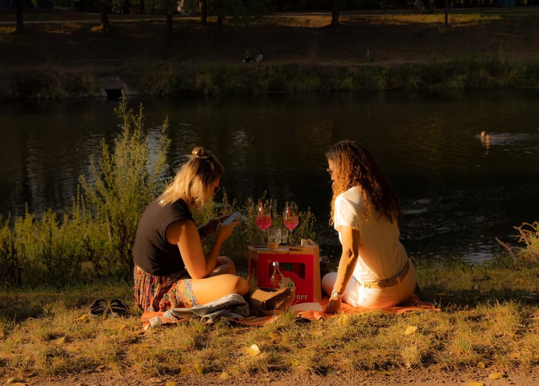 Zwei Frauen beim Picknick am Wasser im Abendlicht mit Spritz